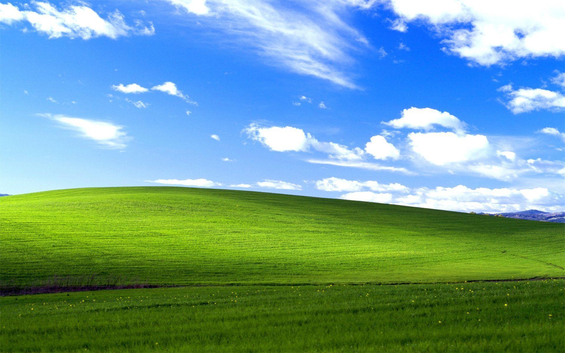 an image of green rolling hills under a partially cloudy bright blue sky.